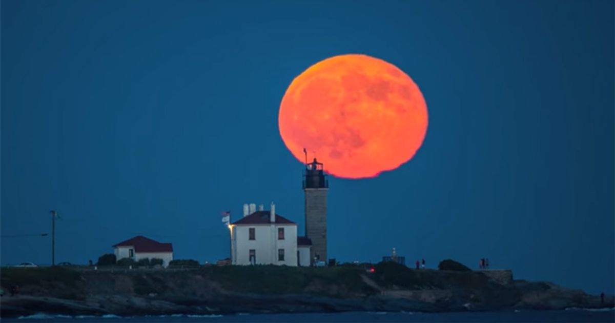 La luna piena si alza in alto sul faro ed è uno spettacolo